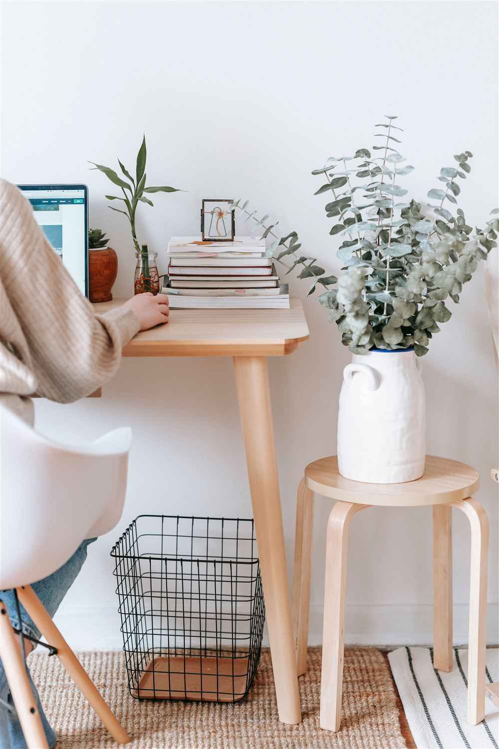 Personne travaillant à un bureau clair, entourée de plantes et de livres